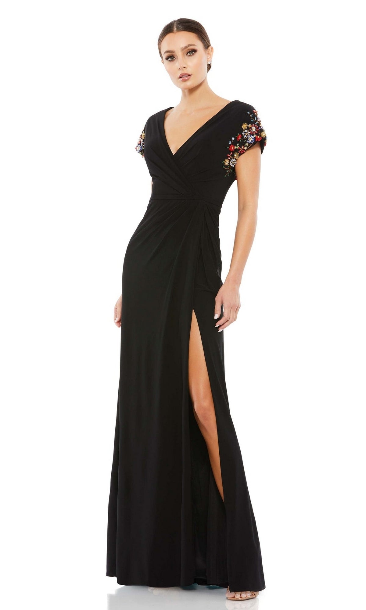 A woman wears the Cap-Sleeve Long Formal Gown: Mac Duggal 55709, featuring a V-neckline, floral embroidered cap sleeves, and a high leg slit.